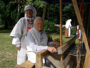 2018 m. Dainų šventėje staklėse sėdi Lietuvos audėjų audėja Monika Kriukelienė, gim. 1920 m.