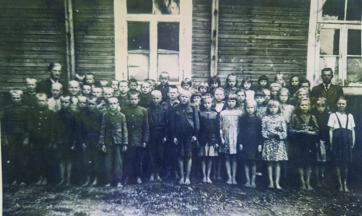 1949 m. nuotraukoje įsiamžino visa mokykla. Tarp vaikų yra ir Elvyros brolis Juozas.
Dešinėje – mokytojas B. Levickas, kairėje – mokytojas Gavėnas